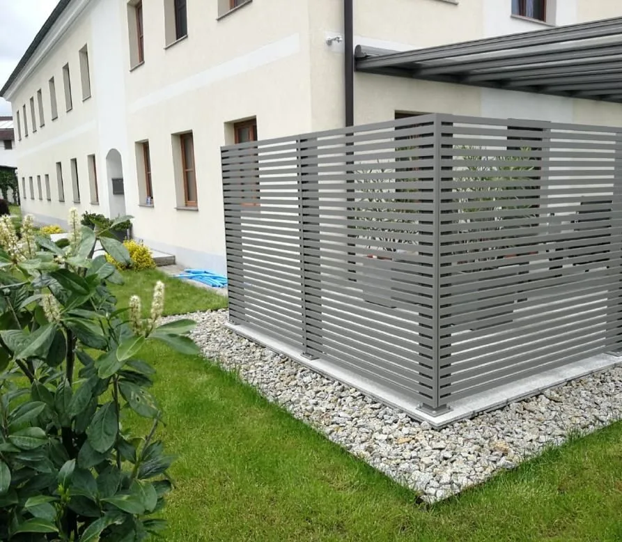 Grauer Lamellensichtschutz an einer Terrasse, auf einem Kiesbett im Rasen