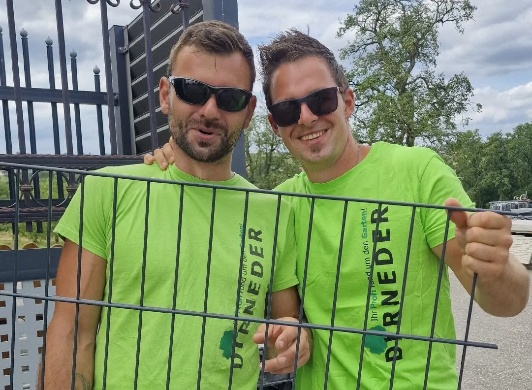 Zwei Zaunmonteure in Dirneder-Shirts halten lachend ein Zaunfeld