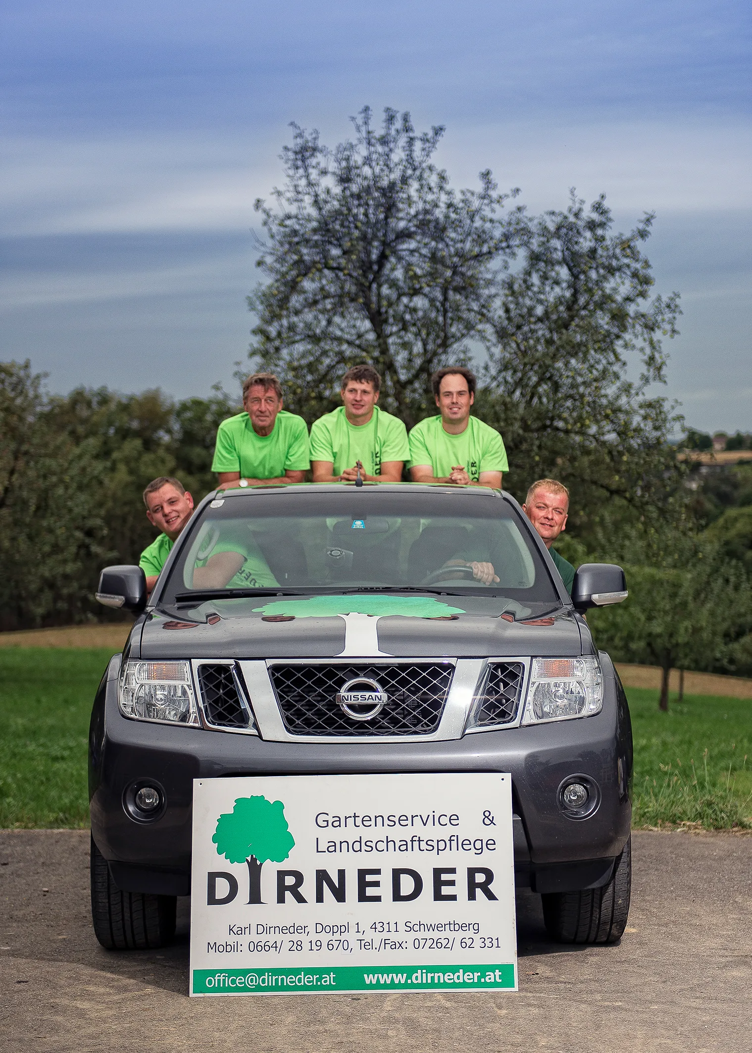 Das Team in grünen Shirts an einem Pickup, davor das Firmenschild Gartenservice und Landschaftspflege Dirneder